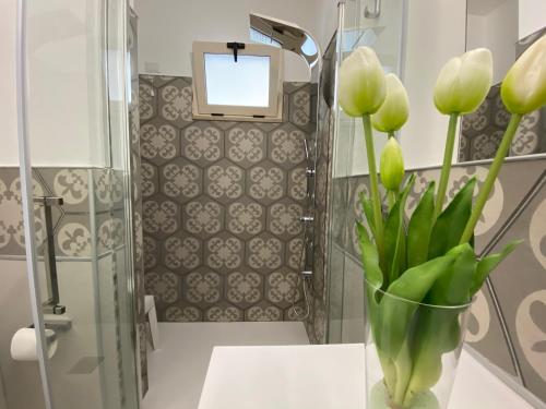 a vase of flowers on a table in a bathroom at Mazzitelli Apartment in Capo Vaticano