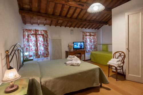 ein Schlafzimmer mit einem grünen Bett und einem TV in der Unterkunft Agriturismo Le 4 Rose in Vescovana