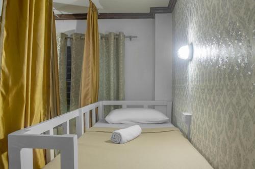 a small bedroom with a bed and a yellow curtain at Davao Hub Bed and Breakfast in Davao City