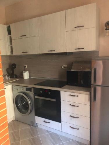 a kitchen with white cabinets and a washer at Апартамент Върбанови in Pomorie