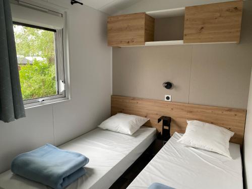 Camping-Caravaning de la Mollière في Groffliers: سريرين في غرفة صغيرة مع نافذة