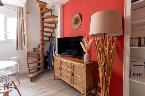 a living room with a tv on a wooden cabinet and a lamp at DUPLEX LE SAINT JEAN in Saumur