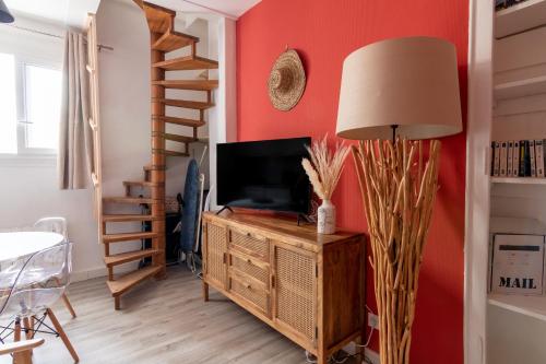 una sala de estar con TV en un armario de madera y una lámpara en DUPLEX LE SAINT JEAN, en Saumur
