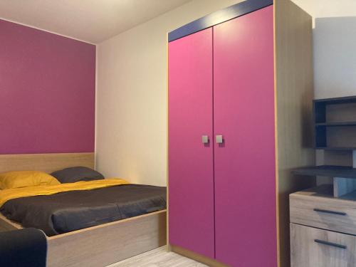 einen rosa Schrank in einem Schlafzimmer mit einem Bett in der Unterkunft Chambres chez l'habitant Hermès à Blagnac in Blagnac