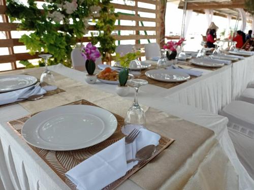 a long table with white plates and silverware on it at Hello Bintan in Kangkakawal