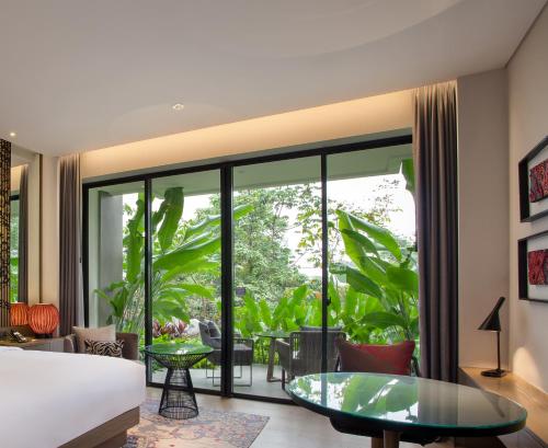 a living room with a bed and a glass table at Pullman Ciawi Vimala Hills Resort in Bogor