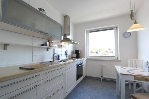 a kitchen with white cabinets and a sink and a window at Leuchtturm in Hörnum