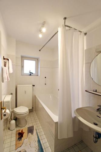 ein Badezimmer mit einer Badewanne, einem WC und einem Waschbecken in der Unterkunft Leuchtturm in Hörnum