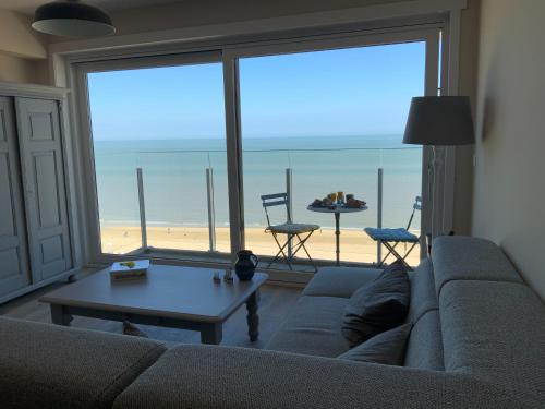 a living room with a couch and a view of the beach at Genieten van de Vlaamse kust met prachtig zeezicht in De Haan