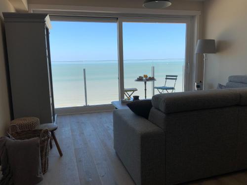 a living room with a couch and a view of the ocean at Genieten van de Vlaamse kust met prachtig zeezicht in De Haan