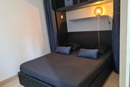 Una cama con almohadas azules y una lámpara en una habitación. en T2 tout neuf au coeur des commerces de Montchat, en Lyon