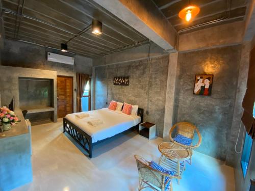 Nan Arena Place في نان: غرفة نوم بسرير وكراسي في غرفة