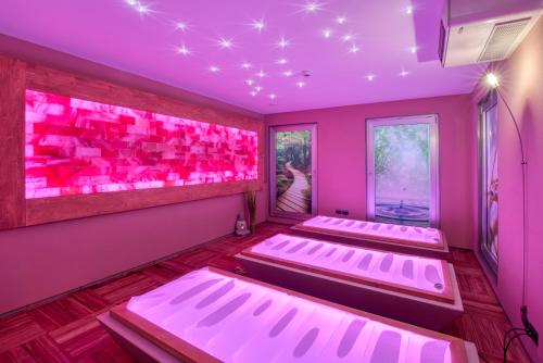 three beds in a room with pink lighting at Residence Al Frantoio in Arco