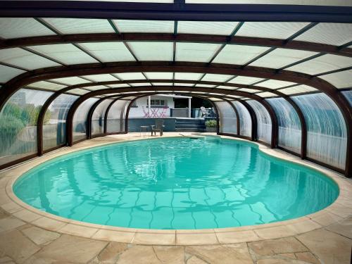 an indoor swimming pool with a glass ceiling at Villa 250m2 avec PISCINE chauffée & SPA & kota-grill & sauna in Saint Die