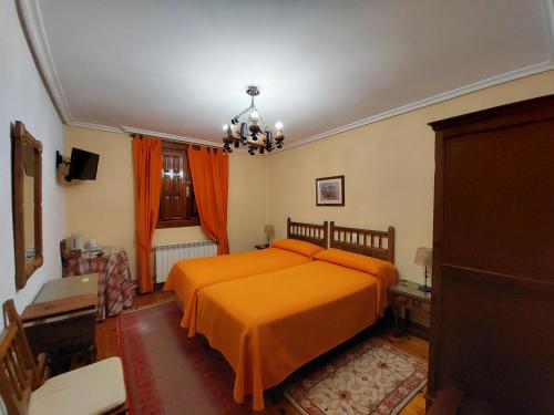 a bedroom with a bed with an orange bedspread at Hosteria Picos De Europa in Potes