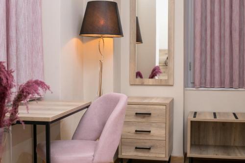 a desk with a pink chair and a lamp at Acropolis Vision in Athens