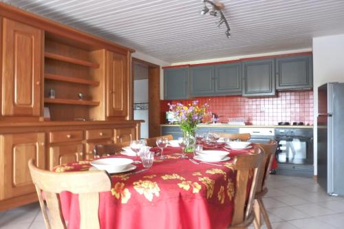 a kitchen with a table with a red table cloth at Gîte Le Chasseron in Les Fourgs