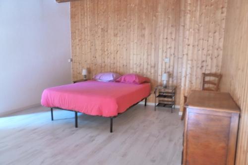 a bedroom with a pink bed and a wooden floor at Gîte Le Chasseron in Les Fourgs
