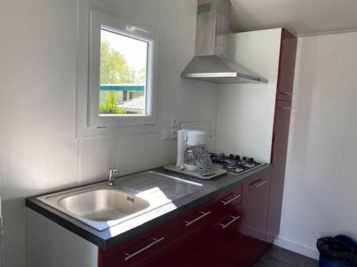 une petite cuisine avec un évier et une fenêtre dans l'établissement Camping-Caravaning de la Mollière, à Groffliers