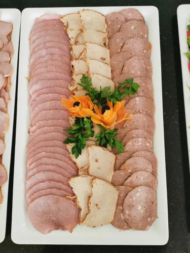 a plate of different types of meats on a table at Lazur Apartamenty in Świnoujście