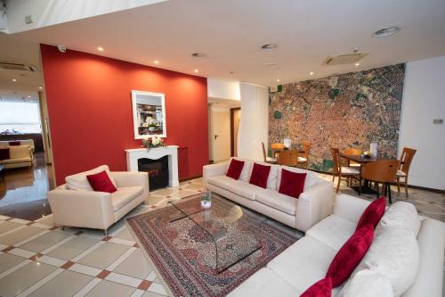 una sala de estar con muebles blancos y una pared roja. en Boutique Hotel Re Enzo en Bolonia