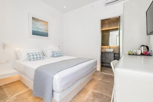 a white bedroom with a bed and a bathroom at Pelican Paros in Parikia