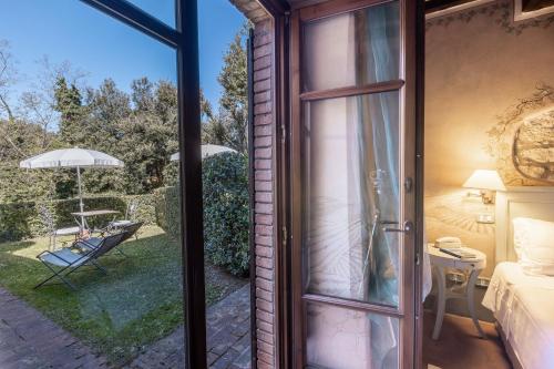 an open glass door to a patio with a chair at La Melosa Resort & Spa in Roccastrada