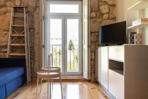 a living room with a tv and a chair and a window at Casa Nina in Porto