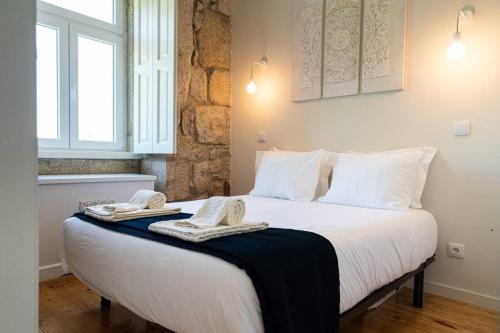 a bedroom with a large white bed with towels on it at Casa Nina in Porto