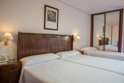 a hotel room with two beds and two lamps at Hotel Museo Los Infantes in Santillana del Mar