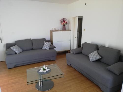 a living room with two couches and a table at Apartman G&L in Grebaštica