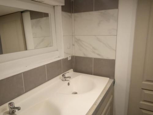 a white bathroom with a sink and a mirror at La Mésange Charbonnière in Lucéram