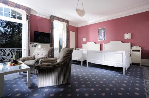a bedroom with white furniture and red walls at Royal St. Georges Hotel Interlaken - MGallery Collection in Interlaken