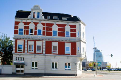 czerwono-biały budynek na rogu ulicy w obiekcie Ferienwohnungen an der Weser w mieście Bremerhaven
