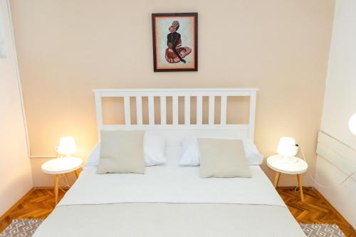 a bedroom with a large white bed with two tables at Apartments Biserka in Božava