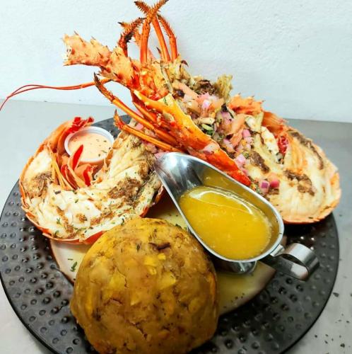 a plate of food with a lobster and a dipping sauce at La Jamaca - An Island Vibe Hotel in La Parguera