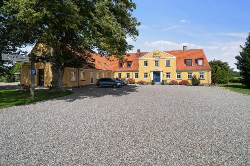 a car parked in front of a yellow house at Otel Vaabensted in Sakskøbing