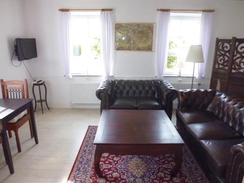 a living room with leather couches and a coffee table at Otel Vaabensted in Sakskøbing
