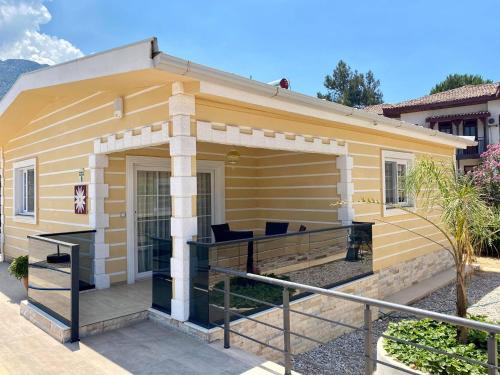 a small yellow house with a large deck at Yalcin Hotel & Villas in Oludeniz