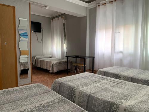 a hotel room with three beds and a mirror at Pensión Bowling in Irún