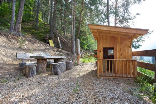 a wooden cabin with a bench and a table at Angerle Hof in Nova Levante