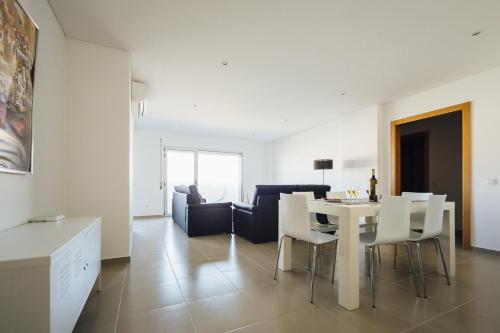 a dining room and living room with a white table and chairs at Carmona - By SCH in São Martinho do Porto