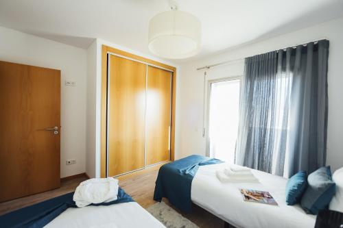 a bedroom with two beds and a large window at Carmona - By SCH in São Martinho do Porto