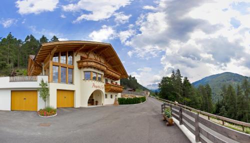 a building with a wooden roof on a road at Angerle Hof in Nova Levante