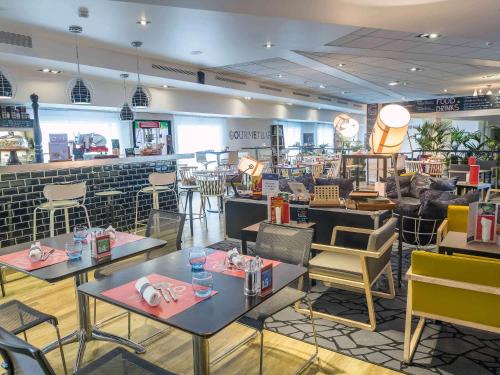 a restaurant with tables and chairs in a room at Novotel Paris Rueil Malmaison in Rueil-Malmaison