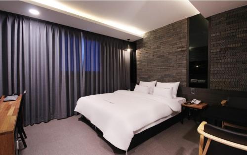 a bedroom with a large white bed and a brick wall at Idea Hotel in Pohang