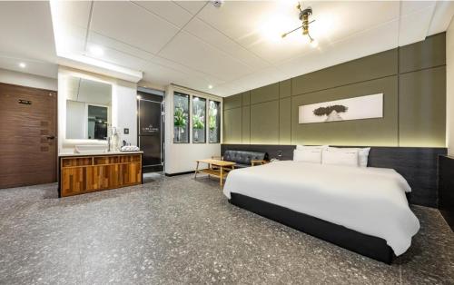 a bedroom with a large white bed and a bathroom at Idea Hotel in Pohang