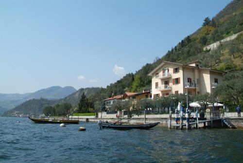 two boats are docked next to a building on the water at La Foresta Monteisola in Monte Isola