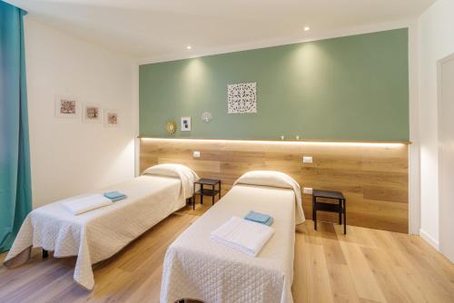 um quarto com três camas e uma parede verde em Dama Bed & Breakfast em Foligno