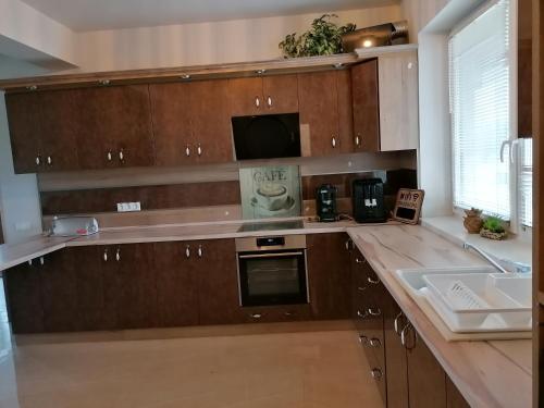 a kitchen with wooden cabinets and a sink and a microwave at ZOLDAV in Nyíradony